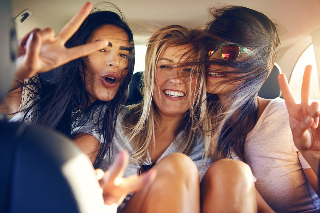 Image of three girls having fun in a car on a road trip