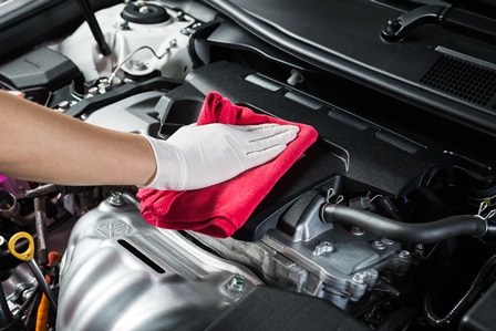 Image of a service tech cleaning the engine of a vehicle