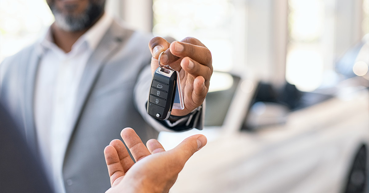 Car key being handed over, symbolizing a vehicle sale or rental transaction in a showroom
