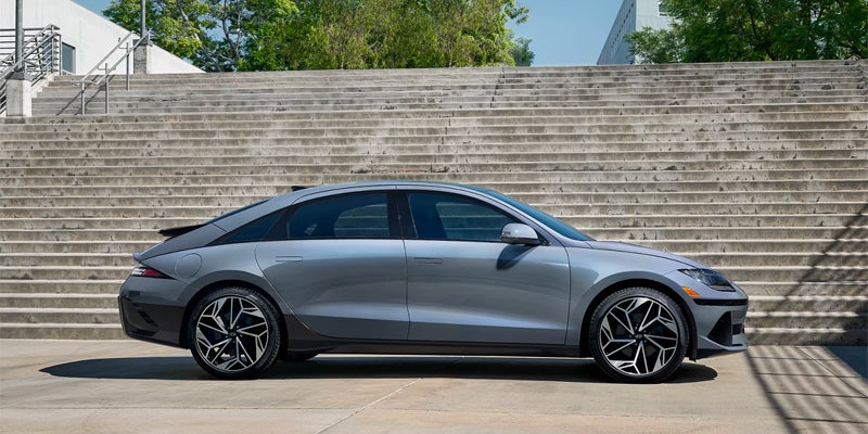 Hyundai Ioniq 6 EV with black geometric-patterned wheels, parked in profile beside concrete steps.